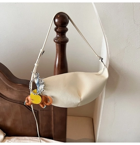 Detail of hobo bag in cream lychee grain leather with cute animal charms and heart chain