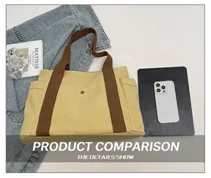Detail view of canvas tote bag featuring multi-pocket design and metal buckle closure