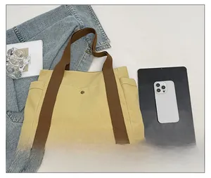 Detail view of canvas tote bag featuring multi-pocket design and metal buckle closure