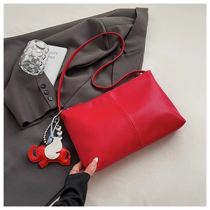 Detail of red pebbled leather tote bag with a cute elephant charm on a grey suit jacket