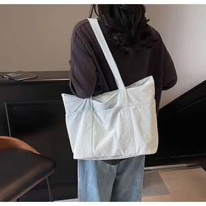 Detail view of large light blue canvas tote bag featuring side pockets and sturdy stitching