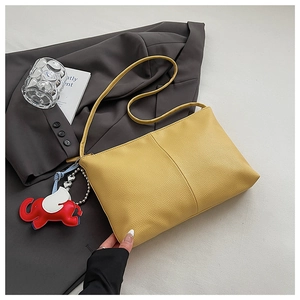 Close-up of yellow pebbled leather tote bag with elephant charm on a blazer background