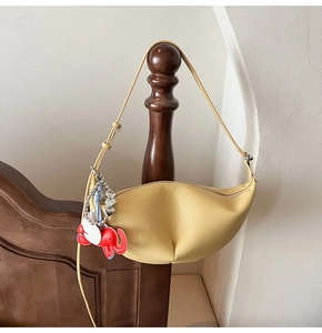 Detail of yellow crescent moon bag with red elephant charm and silver heart chain