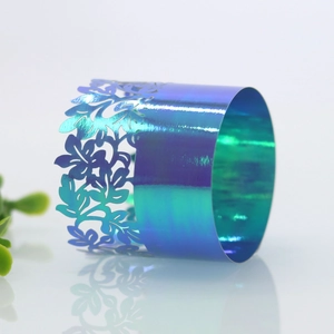 Macro detail of laser-cut napkin ring with floral hollow patterns in blue-green gradient