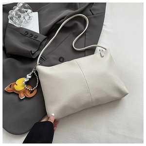 Detail of creamy white pebble leather tote bag featuring a unique elephant leather charm