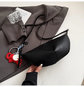 Detail of black crescent crossbody bag in lychee leather with cute elephant pendant