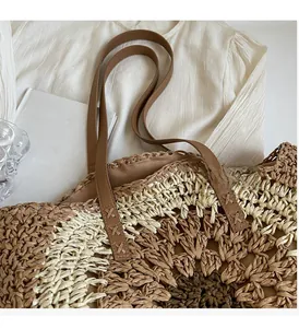 Detail of hand-woven straw bag with durable brown leather handles and sturdy stitching