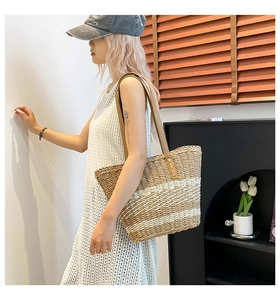 Detail of hand-woven straw tote with striped pattern and premium brown leather straps