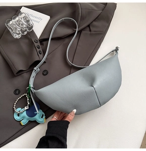 Detail of light blue lychee pattern dumpling bag with cute elephant charm on grey blazer