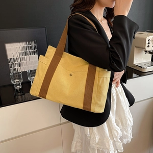 Lifestyle shot of large yellow canvas tote bag with brown straps worn by a model