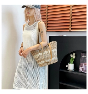Close-up of woven straw tote bag with striped texture and premium leather straps
