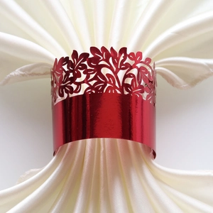 Close-up of laser-cut red napkin ring with floral hollow patterns for wedding decor