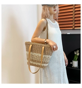 Detail of hand-woven straw tote bag with brown leather handles in a chic room setting