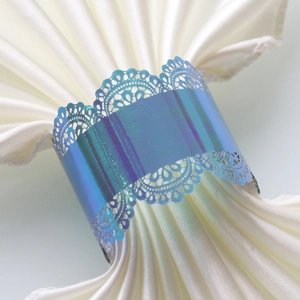 Close-up of laser-cut lace napkin ring in iridescent purple for wedding table decor