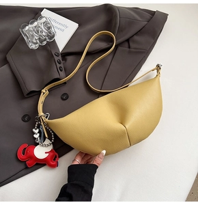 Detail of yellow lychee leather hobo bag with cute elephant charm on a grey blazer