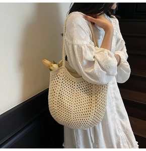 Woman carrying a beige woven hollow tote bag with lining on a staircase background