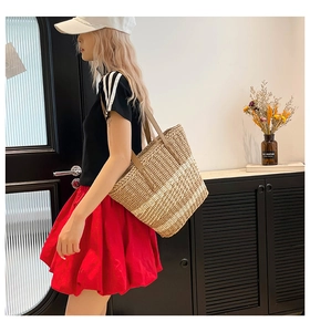 Detail of hand-woven straw tote bag with brown leather shoulder straps for summer beach use