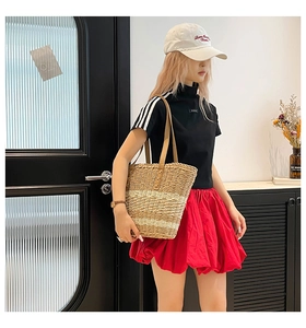 Close-up of a large capacity straw woven tote bag styled with a casual chic outfit