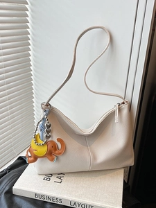 White lychee pattern shoulder bag with elephant pendant and stylish curved design