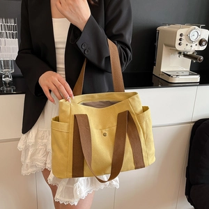 Detailed view of yellow canvas tote bag with brown straps in modern office setting