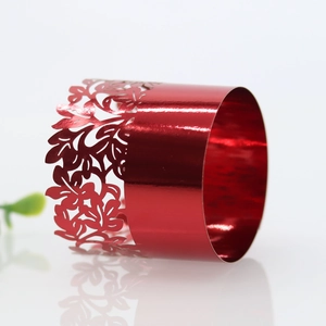 Close-up of laser-cut red metal napkin ring with intricate floral and leaf patterns