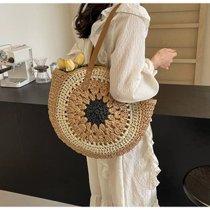 Detail of a large woven straw tote bag with sunflower pattern and leather straps