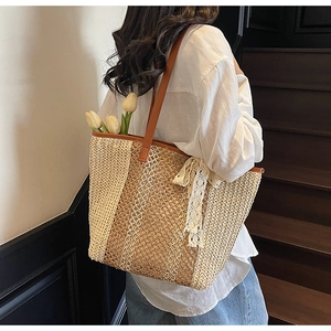 Détail du sac cabas en paille tressée avec bandoulière en cuir et nœud en dentelle