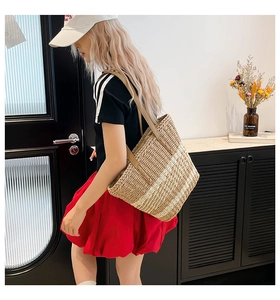 Detail of woven straw tote bag with brown leather handle and tight fiber texture