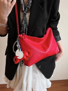 Fashionable red litchi grain leather tote bag with elephant charm on model in black suit
