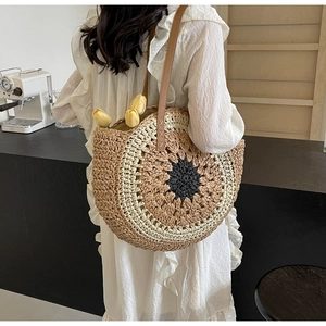 Macro shot of circular straw tote bag with sunflower pattern and leather shoulder straps