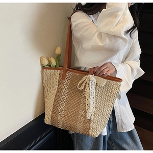 Détail du sac cabas en paille tissée avec motifs ajourés et un nœud en dentelle blanche