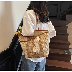 Détail du sac cabas en paille tissée avec bordure en cuir marron et nœud en dentelle