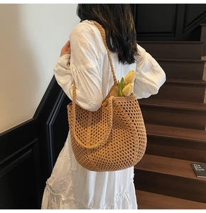 Detail of hand-woven straw tote bag with hollow mesh structure and sturdy shoulder strap