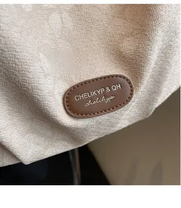 Close-up of beige jacquard fabric with brown leather logo patch on multipurpose tote bag