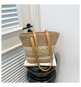 Detail of hand-woven straw tote with brown striped texture and leather handle