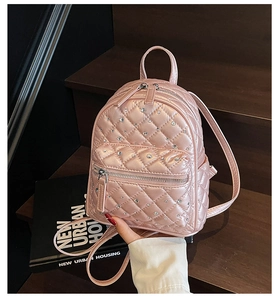 Detail of pink quilted mini backpack with rhinestone decor on dark wood steps