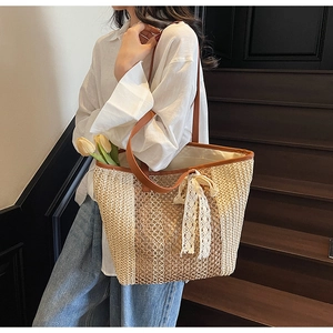 Détail du grand sac cabas en paille tissé avec anses en cuir et nœud en dentelle