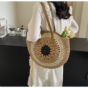 Detail of sunflower pattern woven straw tote bag with brown leather shoulder straps