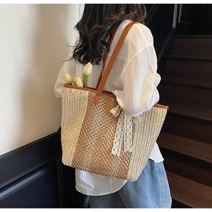 Détail du sac cabas en paille tressée avec anses en cuir marron et nœud décoratif en dentelle