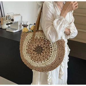 Detail of semi-circle straw tote bag with brown leather strap and woven texture