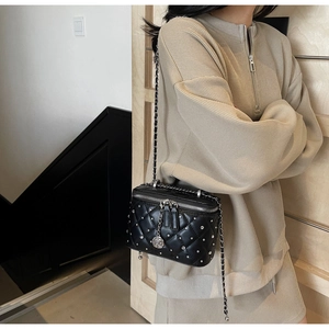 Close-up of black quilted box bag with silver studs and camellia charm zipper