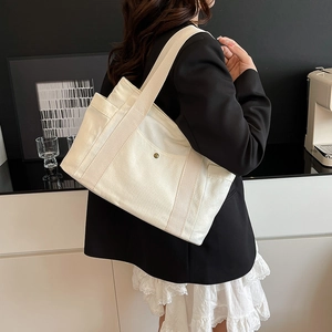Close-up of off-white canvas tote bag showing large capacity and side pocket detail