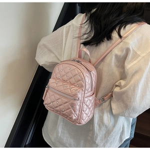 Close-up of pink quilted mini backpack with rhinestone decor and shiny pearl finish
