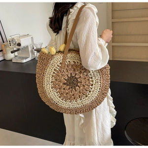 Detailed view of bohemian large round straw bag with brown leather handles in a cafe