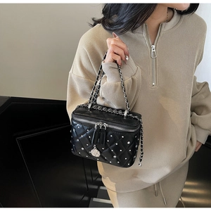 Detail of black quilted crossbody box bag with silver studs and rose charm