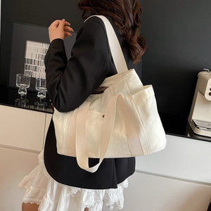 Detail view of the beige canvas tote bag side pocket and thick durable material