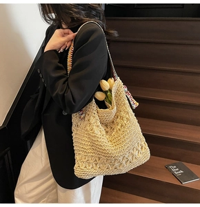 Dettaglio borsa shopper in paglia intrecciata con trama floreale e tracolla colorata