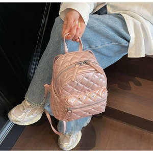 Detail of metallic pink mini backpack with quilted diamond pattern and rhinestone accents