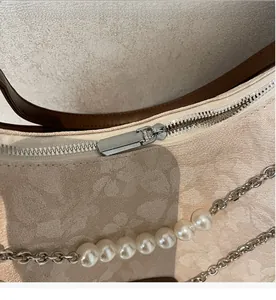Macro shot of silver metal zipper and floral jacquard texture on vintage crossbody bag