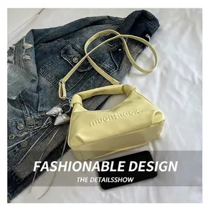 Gros plan d'un sac à main en cuir PU jaune pâle avec logo embossé et breloque nœud argenté